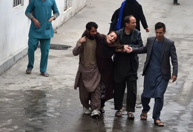 Afghan men assist a woman, who collapsed after a massive suicide blast at a Shiite mosque, to the Estiqlal Hospital in Kabul on November 21, 2016. A massive suicide blast at a Shiite mosque in Kabul killed at least 27 people and wounded 35 as worshippers gathered for a religious ceremony, officials said. (Photo by Wakil Kohsar/AFP Photo)