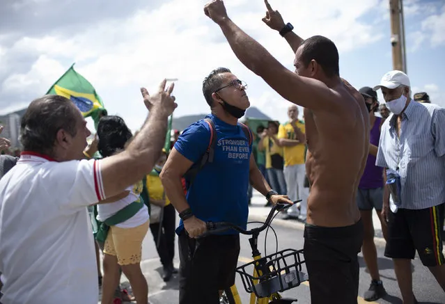 An opponent, center left, confronts supporters of Brazilian President Jair Bolsonaro during a demonstration supporting Bolsonaro after leaders of all three branches of the armed forces jointly resigned following the replacement of the defense minister, on Copacabana beach in Rio de Janeiro, Brazil, Wednesday, March 31, 2021. (Photo by Silvia Izquierdo/AP Photo)