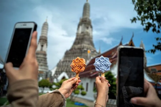 People take pictures of ice cream shaped like tiles of the famous Wat Arun temple, or Temple of Dawn, in Bangkok, Thailand on July 8, 2023. (Photo by Athit Perawongmetha/Reuters)