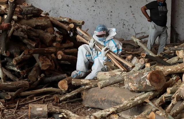 A family member carries wood to prepares funeral pyres for their relative who died from COVID-19 disease before cremation at Ghazipur cremation ground in New Delhi on April 26, 2021. In India the highest single-day spike in coronavirus infection. The report recorded 352,991 new Covid-19 cases and 2,812 deaths in the last 24 hours amid an oxygen crisis. (Photo by Naveen Sharma/SOPA Images/Rex Features/Shutterstock)