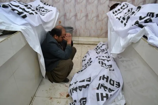 A Pakistani mourner grieves alongside bodies of blast victims near a polio vaccination center in Quetta, Pakistan, January 13, 2016. (Photo by Banaras Khan/AFP Photo)