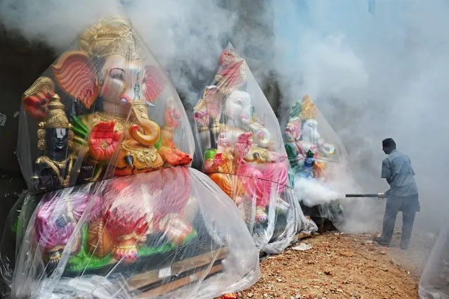 A municipal worker fumigates a housing colony as a preventive measure against mosquito-borne diseases next to idols of the elephant-headed Hindu deity “Ganesha” ahead of the Ganesh Chaturthi festival in Chennai on September 13, 2023. (Photo by R. Satish Babu/AFP Photo)