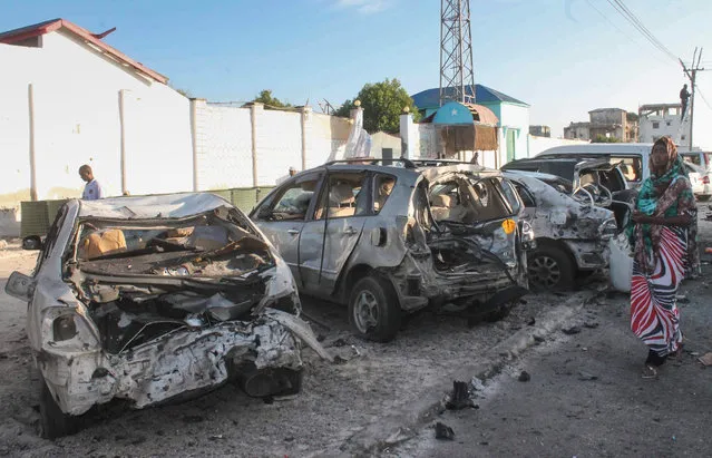 A woman walks in front of vehicles marred by explosions after Somali security forces took control over of the restaurant and ended the siege where gunmen exploded car bombs and opened fire on people the night before, 22 January 2016. At least 20 people were killed in two suicide bombings targeting a popular beach hotel and a restaurant 21 January in the Somali capital Mogadishu, police and witnesses said. A car laden with explosives rammed into the Beach View Hotel on Lido beach, after which four suspected militants from Islamist group al-Shabaab opened fire at the hotel, police representative Ahmed Aloley said. (Photo by Said Yusuf Warsame/EPA)