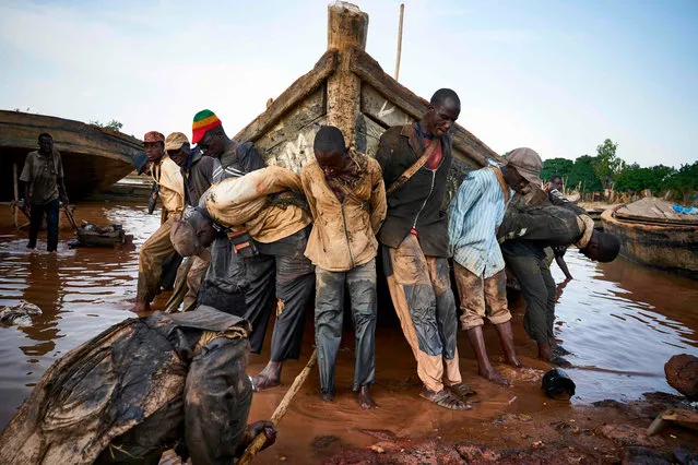 Malian workers haul out a boat they use to carry sand collected from the river bed during a routine maintenance on October 7, 2018, in the port of Bamako. (Photo by Michele Cattani/AFP Photo)