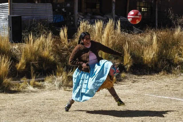 An Aymara indigenous woman plays football during a championship in the Aymara district of Juli in Puno, southern Peru, on July 16, 2022. (Photo by Carlos Mamani/AFP Photo)