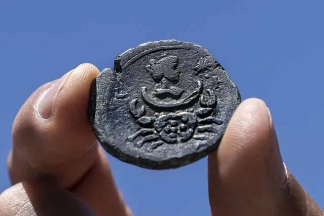 A rare, nearly 1,850-year-old bronze coin discovered off the Israeli coastal city of Haifa is on display at Israel's Antiquities Authority office in Jerusalem, Tuesday, July 26, 2022. The coin bears the image of the zodiac sign Cancer behind a depiction of the moon goddess Luna. Experts said Monday the coin was minted in Alexandria, Egypt, under the rule of the Roman Emperor Antoninus Pius in the second century. The antiquities authority says it is the first time such a coin has been found off the Israeli coast. (Photo by Tsafrir Abayov/AP Photo)