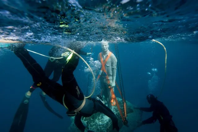 Divers ensure the sculpture makes a safe descent. (Photo by Cat Vinton)