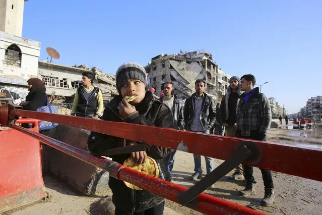 A boy eats bread while residents wait to evacuate Babila town, after what activists said was a new ceasefire between forces loyal to Syria's president Bashar Al-Assad and rebel fighters in the towns of Babila and Beit-Sahm in southeast Damascus January 14, 2015. (Photo by Reuters/Stringer)