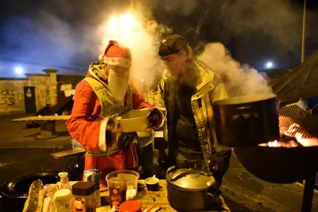 A man dressed as Santa Claus takes a coffee with yellow vests (Gilet jaune) protestors blocking (gilets jaunes) an oil depot near Le Mans, northwestern France, on December 10, 2018. (Photo by Jean-François Monier/AFP Photo)