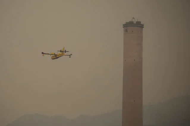 A Spanish firefighting plane pours water on a fire near the Kemerkoy Power Plant, a coal-fueled power plant, in Milas, Mugla in southwest Turkey, Thursday, August 5, 2021. A wildfire that reached the compound of a coal-fueled power plant in southwest Turkey and forced evacuations by boats and cars, was contained on Thursday after raging for some 11 hours, officials and media reports said. (Photo by Emre Tazegul/AP Photo)