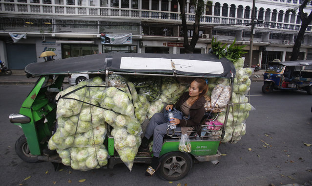 A Thai vendor sits on Thai tuk tuk or auto rickshaw and waits for a driver after loading vegetable for sale at market in Bangkok, Thailand, Monday, January 9, 2017. Tuk-Tuk is a popular form of transport in Thailand. (Photo by Sakchai Lalit/AP Photo)