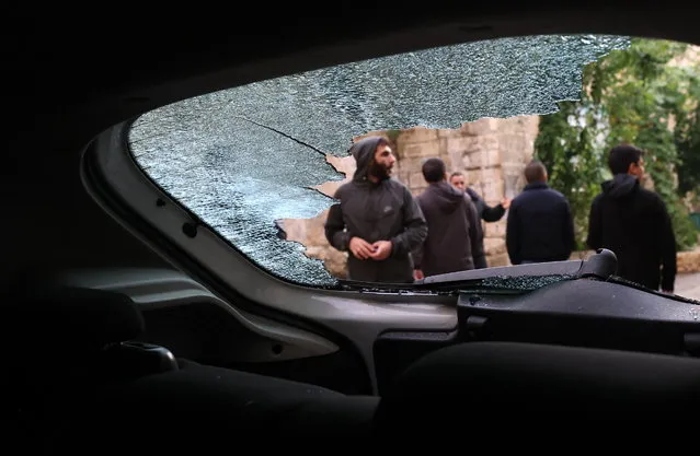 Palestinians look at a damaged vehicle following an Israeli troops raid in the West Bank city of Nablus, 07 December 2023. According to the Palestinian Health Ministry, at least three Palestinans were injured in clashes with Israeli troops during the raid. (Photo by Alaa Badarneh/EPA)