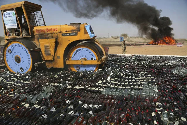 Pakistani authorities smash confiscated bottles of alcohol and burn drugs in Karachi, Pakistan, Monday, February 11, 2019. The Pakistani Anti-Narcotic Force is taking strict measures to stop drug trafficking from neighboring Afghanistan and Pakistani tribal areas. (Photo by Muhammad Rizwan/AP Photo)