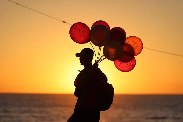 A Palestinian vendor sells balloons next to the Mediterranean Sea shore in Gaza City, on the second day of Eid al-Adha holiday, on July 21, 2021. The Eid al-Adha, or “Feast of Sacrifice”, marks the end of the annual pilgrimage or Hajj to the Saudi holy city of Mecca and is celebrated in remembrance of Abraham's readiness to sacrifice his son to God. (Photo by Mohammed Abed/AFP Photo)
