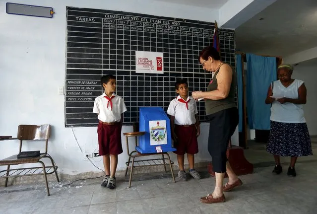 Women walk to the ballot box to cast their votes at a polling station set up at a central office of the Committees for the Defence of the Revolution (CDR) for this district in Havana April 19, 2015. The CDRs, created by former Cuban leader Fidel Castro, are assigned to every block of houses in Cuba, to provide medical assistance if needed, and to monitor people's movements and activities in each neighbourhood. (Photo by Reuters/Stringer)