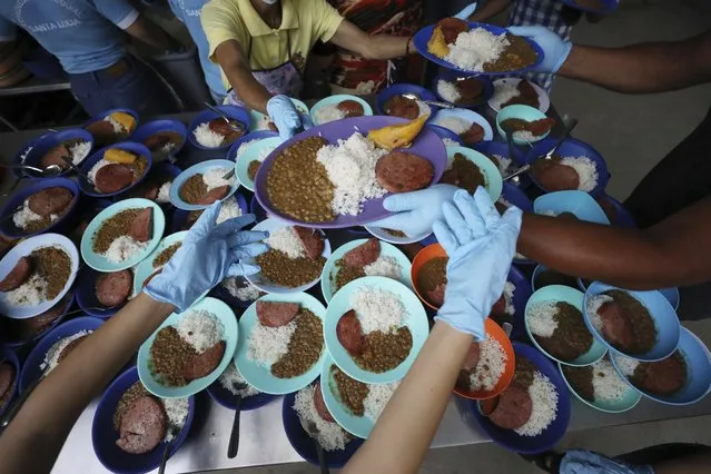 Volunteers prep free lunch plates with lentils, a slice of bologna, rice and a piece of plantain at the “Divina Providencia” migrant shelter in La Parada, near Cucuta, Colombia, on the border with Venezuela, Monday, February 18, 2019. The director of the shelter says they serve about 4,500 lunches per day, mostly to Venezuelan migrants, everyday of the week with the exception of Sunday. (Photo by Fernando Vergara/AP Photo)