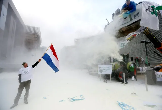 A milk producer waves a Dutch flag as farmers spray powdered milk to protest against dairy market overcapacity outside a meeting of European Union agriculture ministers in Brussels, Belgium, January 23, 2017. (Photo by Francois Lenoir/Reuters)