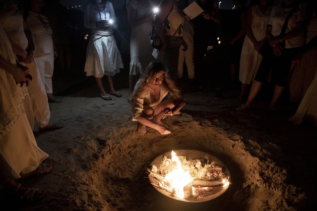Women take part in a Tashlich ceremony, where they wrote down things they want to release before casting them into a fire, on the beach in Tel Aviv, Israel, Tuesday, September 14, 2021. Tashlich, which means 'to cast away' in Hebrew, is the practice by which Jews go to a large flowing body of water and symbolically 'throw away' their sins by throwing a piece of bread, or similar food, into the water before the Jewish holiday of Yom Kippur, the holiest day in the Jewish year which starts at sundown Wednesday. (Photo by Maya Alleruzzo/AP Photo)
