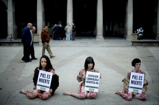 Passersby observe activists with AnimaNaturalis who are covered with artificial blood, wearing furs and holding signs reading “The skin of animals is death”, during a protest against the use of fur in Vitoria, April 19, 2015. (Photo by Vincent West/Reuters)