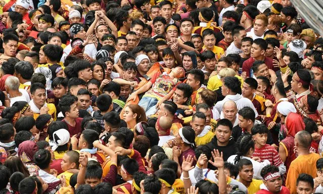 People help emergency personnel carry a Catholic devotee who passed out during an annual religious procession held in honour of the so-called Black Nazarene in Manila on January 9, 2024. Hundreds of thousands of Catholic faithful swarmed a historic statue of Jesus Christ as it was pulled through the streets of the Philippine capital on January 9, in one of the world's biggest displays of religious devotion. (Photo by Ted Aljibe/AFP Photo)