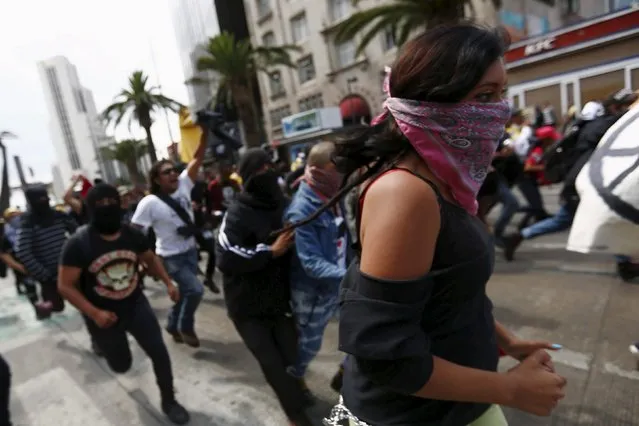 Protesters run during a march for Labor Day in Mexico City May 1, 2015. (Photo by Edgard Garrido/Reuters)