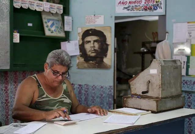 Wilfredo, 47, a worker of a subsidised state store, or “bodega”, where Cubans can buy basic products with a ration book they receive annually from the government, works near an image of revolutionary fighter Ernesto “Che” Guevara in Havana March 15, 2016. (Photo by Enrique de la Osa/Reuters)