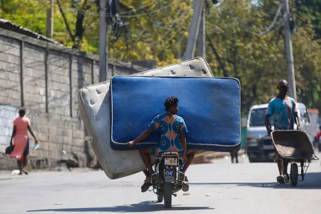 Residents transport mattresses on a motorcycle in Port-au-Prince, Haiti, Monday, March 4, 2024. Authorities ordered a 72-hour state of emergency starting Sunday night following violence in which armed gang members overran the two biggest prisons and freed thousands of inmates over the weekend. (Photo by Odelyn Joseph/AP Photo)