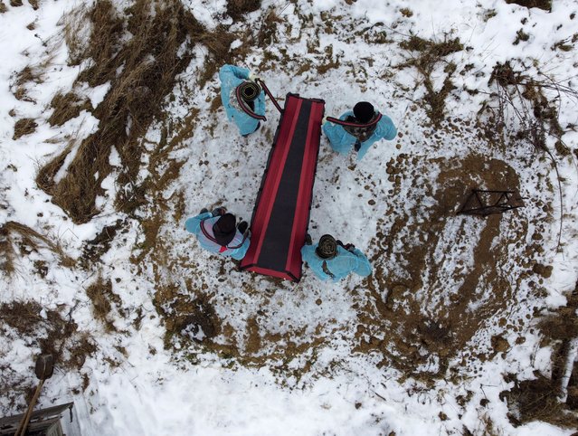 Grave diggers wearing protective face masks and wraps bury a person having no next of kin at a cemetery in the town of Tara in the Omsk region, Russia on November 12, 2021. Picture taken with a drone. (Photo by Alexey Malgavko/Reuters)