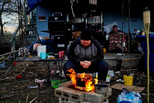 Christopher Bowlin, 24, sits by a fire outside his home to boil eggs and stay warm after a devastating outbreak of tornadoes ripped through several U.S. states, in Mayfield, Kentucky, U.S. December 11, 2021. (Photo by Cheney Orr/Reuters)