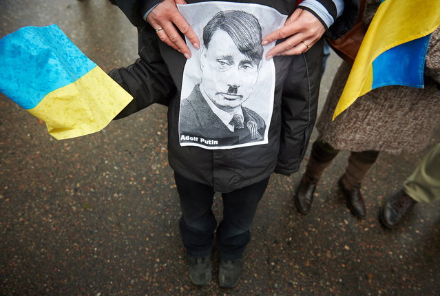 A protester holds a portrait of Russian President Vladimir Putin during a demonstration organized by a trade union “Solidarity” against the Russian military actions in Crimea, in front of the Russian Consulate General headquarters in Gdansk, Poland, March 15, 2014. (Photo by Adam Warzawa/EPA)