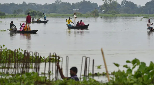 In this Friday, July 12, 2019 photo, Indian villagers cross floodwaters on country boats in Ashighar village, Morigaon district, in the northeastern Indian state of Assam. Rain-triggered floods and mudslides have left a trail of destruction across northeastern India, killing at least a dozen people and affecting over a million, officials said Saturday. (Photo by AP Photo/Stringer)