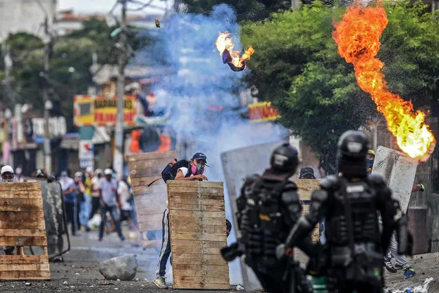 Demonstrators clash with riot police during a protest against a tax reform bill launched by Colombian President Ivan Duque, in Cali, Colombia on April 29, 2021. Workers' unions, teachers, civil organizations, indigenous people and other sectors reject the project that is underway in the Congress, considering that it punishes the middle class and is inappropriate in the midst of the crisis unleashed by the COVID-19 pandemic. (Photo by Paola Mafla/AFP Photo)