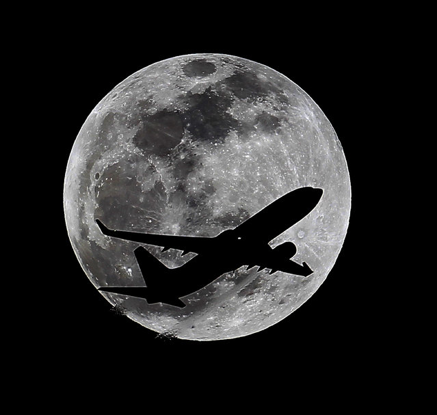An airliner crosses the moon's path, Monday, April 14, 2014, above Whittier, Calif., approximately one hour before a total lunar eclipse. Then, on April 29, the Southern Hemisphere will be treated to a rare type of solar eclipse. In all, four eclipses will occur this year, two lunar and two solar. (Photo by Nick Ut/AP Photo)