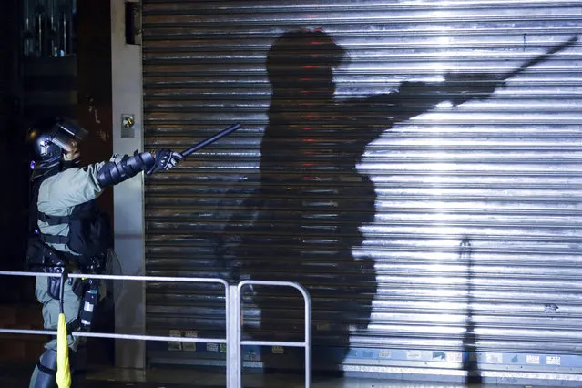 A riot policeman gestures as police disperse the residents and protesters at Sham Shui Po district in Hong Kong, Wednesday, August 7, 2019. Protesters surrounded a Hong Kong police station to demand the release of a university student arrested for apparently buying laser pointers, sparking the latest confrontation in the Chinese city. (Photo by Vincent Thian/AP Photo)