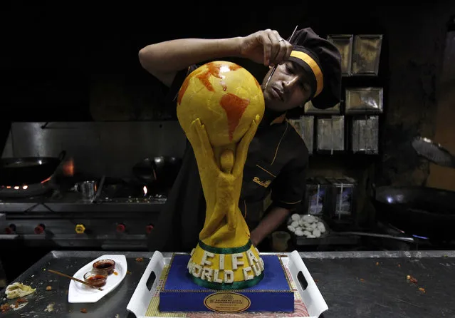 Shambu Shaw, 28, a confectioner, puts the finishing touches to a replica of a one and a half feet tall and six kg FIFA World Cup trophy, made of sweets, in a bakery workshop in Kolkata, ahead of the 2014 World Cup in Brazil, May 29, 2014. (Photo by Rupak De Chowdhuri/Reuters)
