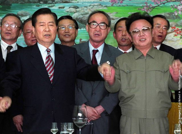 South Korean President Kim Dae-jung, left, and North Korean leader Kim Jong Il, right, hold hands as they sing a song titled We Are Hoping For Reunification