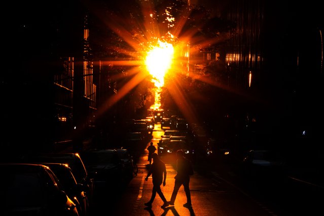 People cross a street at sunset in Manhattan, New York City on June 10, 2024. (Photo by Charly Triballeau/AFP Photo)