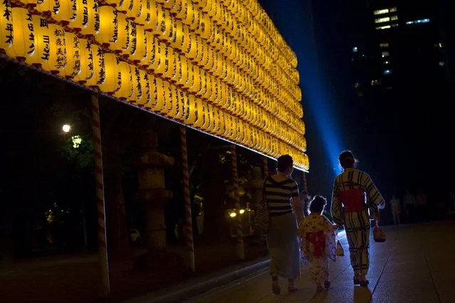 People walk past a wall of lanterns as they leave the annual Mitama Festival at the Yasukuni Shrine in Tokyo, Japan, July 13, 2015. (Photo by Thomas Peter/Reuters)