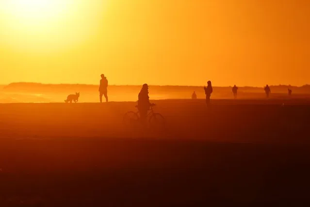 Tourists and locals enjoy walking in the winter sun during a sunset at the Roberta beach, amid the outbreak of the coronavirus disease (COVID-19), as the Spanish government considers the sixth wave of COVID-19 to be coming to an end, in Barcelona, Spain on February 1, 2022. (Photo by Nacho Doce/Reuters)