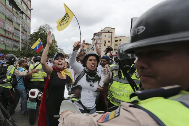 Demonstrators shout “Police don’t support the dictatorship” during a May Day march by opponents of President Nicolas Maduro in eastern Caracas, Venezuela, Monday, May 1, 2017. Venezuelans are taking to the streets in dueling anti- and pro-government May Day demonstrations as an intensifying protest movement enters its second month. (Photo by Fernando Llano/AP Photo)
