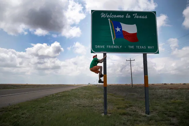 Hunter Anderson, meteorology student from St. Cloud State University and intern with the Center For Severe Weather Research, climbs a “Welcome to Texas” sign en route to a tornado research mission, May 9, 2017 near Dalhart, Texas. Tuesday was the group's second day in the field for the 2017 tornado season for their research project titled “TWIRL”. (Photo by Drew Angerer/Getty Images)