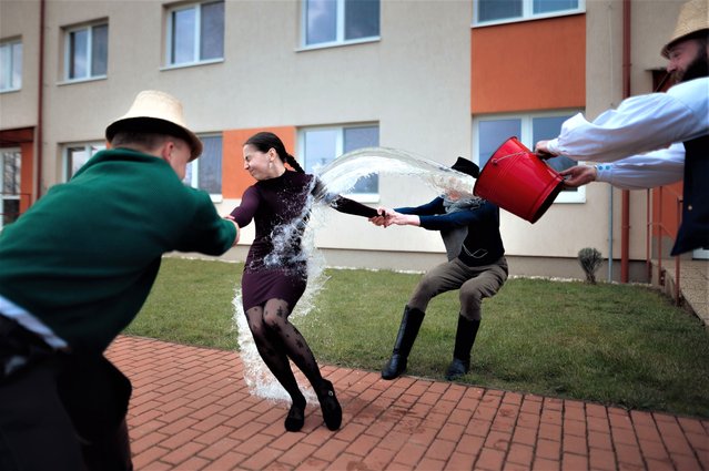 Boys and younger men from the Ilosvai Selymes Peter folk dance group pour buckets of cold water on a girl as they attend the traditional watering of local girls on Easter Monday in Komarovce, Velke Trakany, Slovakia on April 10, 2023. During Easter Holy Week, the ancient tradition of Easter sprinkling known as “watering of the girls” when Hungarian boys visit their female friends, recite poems, and pour water on them, and in exchange the girls offer the boys food and drink. (Photo by Robert Nemeti/Anadolu Agency via Getty Images)