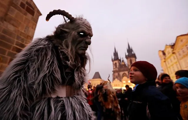 A child looks at a reveller dressed as devil in Prague city centre on the eve of Saint Nicholas Day, Czech Republic, December 5, 2019. (Photo by David W. Cerny/Reuters)