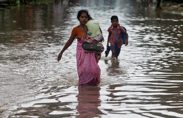 A schoolboy and a woman carrying a child wade through a flooded road after heavy rains in Agartala, India June 1, 2017. (Photo by Jayanta Dey/Reuters)