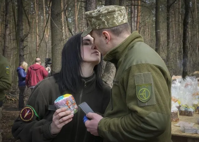 A military couple share a tender moment after an Easter cakes blessing ceremony on Easter eve at a military position outside Kyiv, Ukraine, Saturday, April 23, 2022. (Photo by Efrem Lukatsky/AP Photo)
