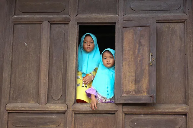Girls look out from a window during a visit to Wadi Hussein Mosque, also known as the Talo Mano Mosque – one of the oldest mosques in Thailand – on a public holiday following Eid al-Fitr, which marks the end of the Muslim holy month of Ramadan, in the southern Thai province of Narathiwat on May 4, 2022. (Photo by Tuwaedaniya Meringing/AFP Photo)