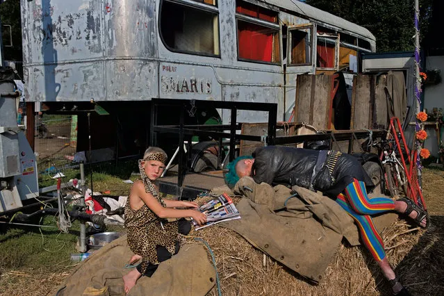 Boy reads as his mum recovers from a long night in Lost Vagueness, Glastonbury, 2005. (Photo by Barry Lewis/The Guardian)