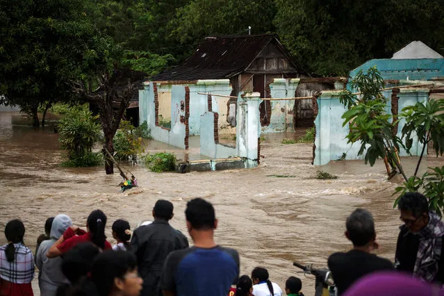People stand in front of a flooded area in Kampung Sewuresidential area in Solo, Central Java province, Indonesia, June 19, 2016. (Photo by Maulana Surya/Reuters/Antara Foto)