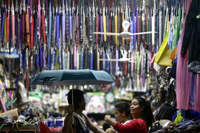 Filipinos buy umbrellas and raincoat inside a store at a public market in Manila, Philippines, June 17, 2014. Different kinds of rain and flood protection suits are sold in Manila public market in preparation for the rainy season and flooding in the Philippines. (Photo by Ritchie B. Tongo/EPA)
