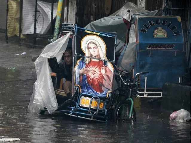 A Filipino sits on his tri-bike in a flooded area due to typhoon Rammasun in Manila, Philippines, 16 July 2014. Typhoon Rammasun pounded the Philippine capital on 16 July, cutting off power and forcing the Manila to shut down after leaving one person dead in an eastern province. Hundreds of thousands of people fled their homes as Rammasun, locally called Glenda, made landfall on 15 July in the eastern Philippines. (Photo by Dennis M. Sabangan/EPA)